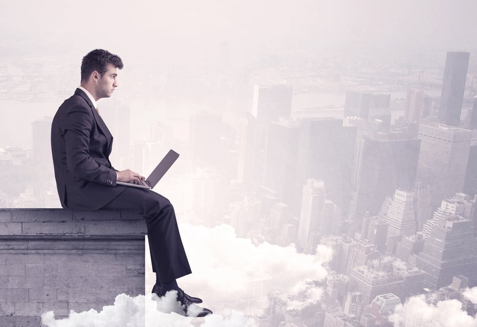 An elegant young businessman sitting on the edge looking over urban city landscape with clouds concept